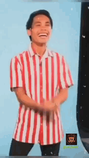 a man wearing a red and white striped shirt is laughing and dancing .