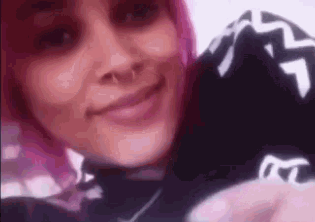 a close up of a woman with pink hair and a nose ring .