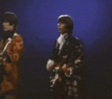 two men are playing guitars and singing on a stage in front of a blue background .