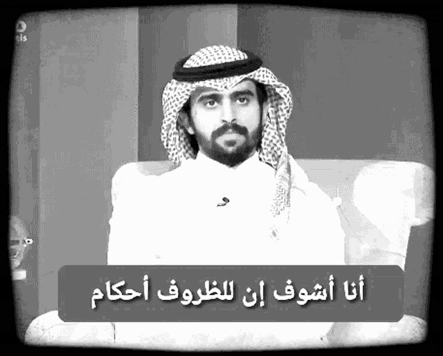 a black and white photo of a man with arabic writing on a sign