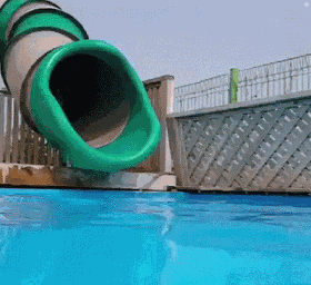 a green water slide is going down a pool