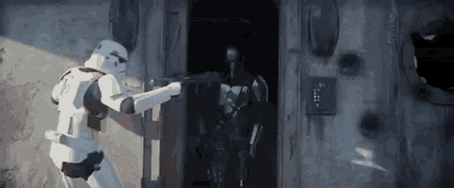a storm trooper and a mandalorian are standing in front of a door .