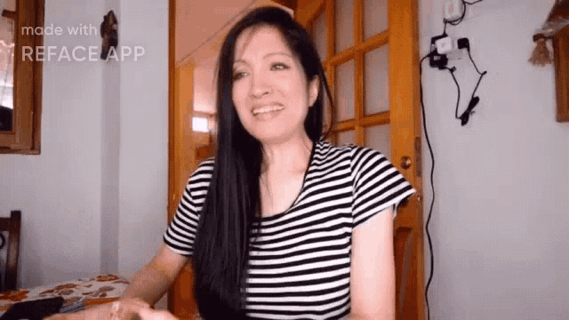 a woman wearing a striped shirt is smiling in a room .