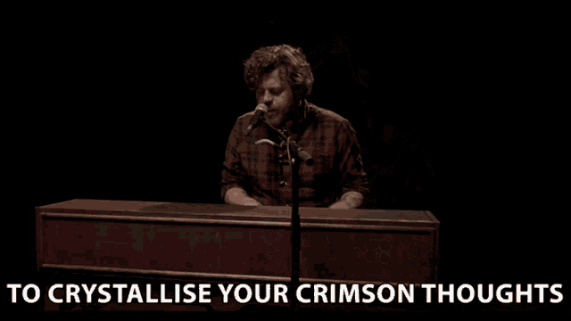 a man singing into a microphone with the words to crystallise your crimson thoughts