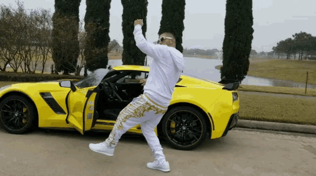 a man is standing in front of a yellow sports car with the door open
