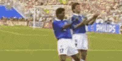 two soccer players standing on a field with their arms crossed .