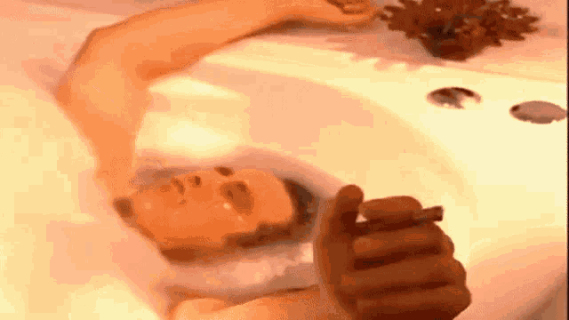 a man is laying in a bathtub while smoking a cigarette