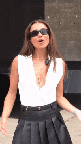 a woman wearing sunglasses and a white top has a louis vuitton belt around her waist