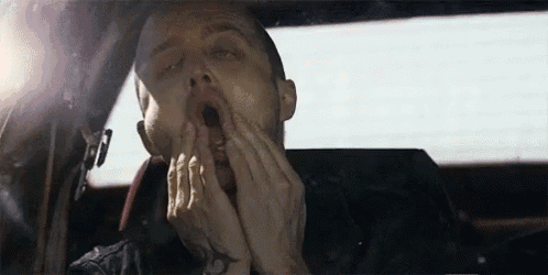 a man is yawning while sitting in a car with his mouth open .