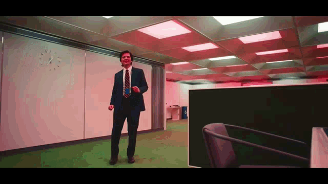 a man in a suit and tie is dancing in front of a wall with a clock on it