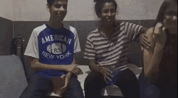 a group of people are sitting on a couch and one of them is wearing a shirt that says american