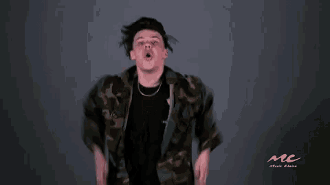 a man in a camouflage jacket is squatting down with his mouth open and screaming .