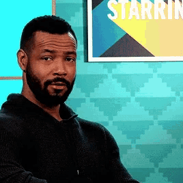 a man with a beard is sitting in front of a starrin sign