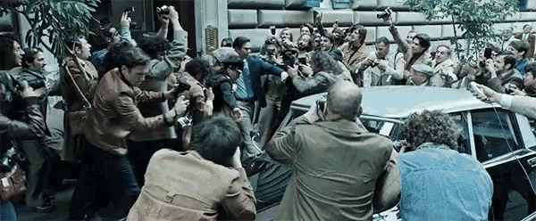 a group of people are taking pictures of a car