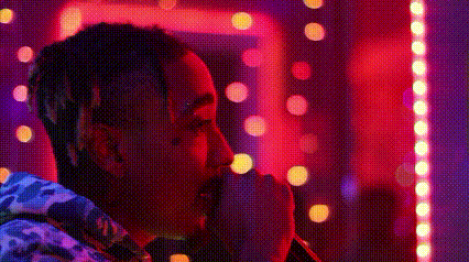 a man with dreadlocks is standing in front of a crowd of people in a club .