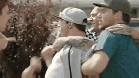 a group of young men are hugging each other while standing next to each other .