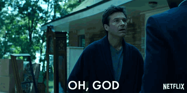 a man in a robe is standing in front of a house and says " oh god "
