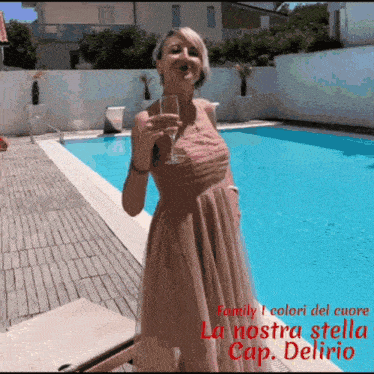 a woman holding a glass of wine in front of a pool