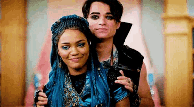 a man and a woman are posing for a picture together . the woman has blue hair .