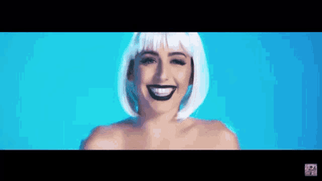 a woman with a white wig and black makeup is smiling .