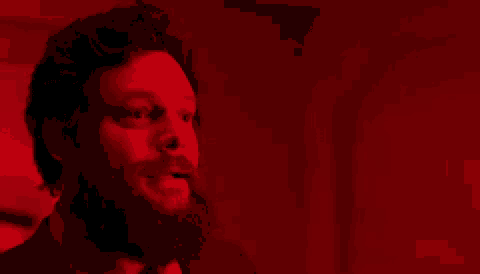 a man with a beard is saying `` i can trust you '' in a red lighted room .