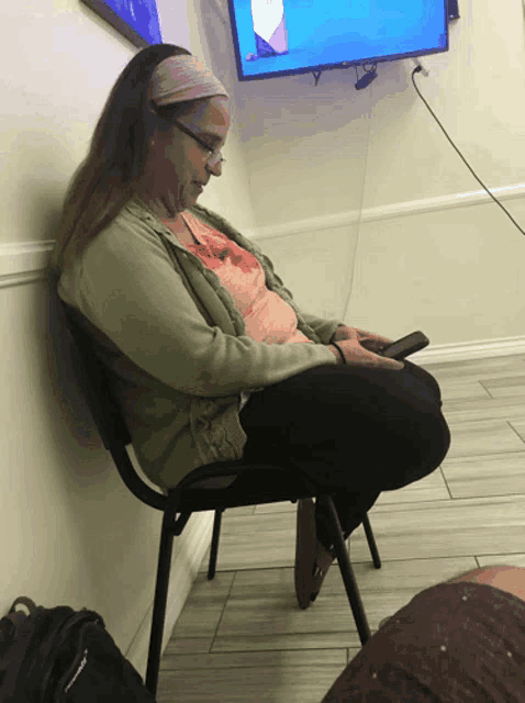 a woman sits in a chair in front of a television