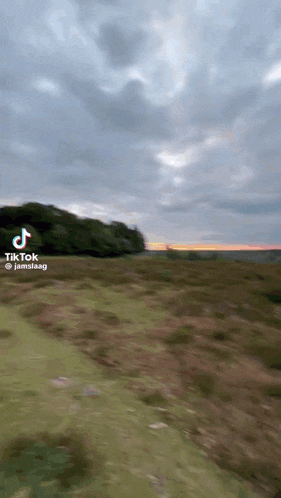 a tiktok video of a sunset over a grassy hillside