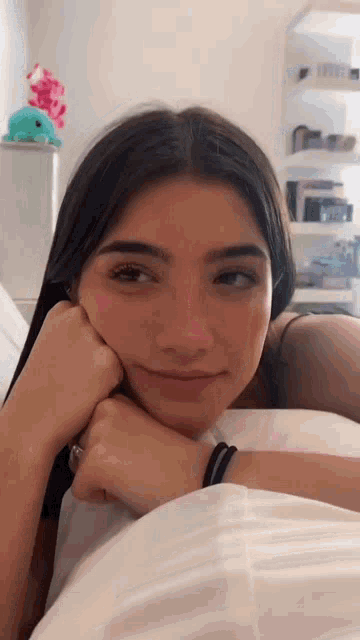 a girl is laying in bed with her head resting on her hand