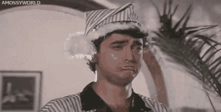 a man wearing a striped shirt and a santa hat is making a funny face .