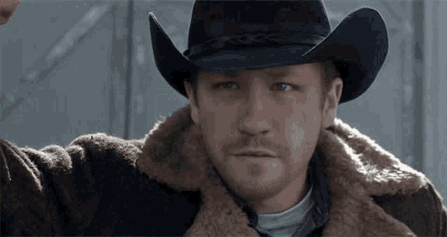 a man wearing a cowboy hat and fur coat