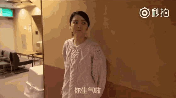 a woman in a pink sweater stands in front of a mirror in a room .