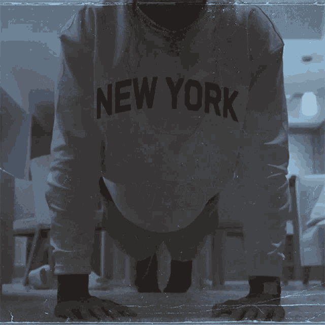 a man is doing push ups wearing a new york sweatshirt