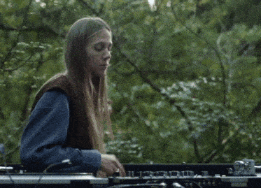 a woman in a blue shirt is playing a keyboard