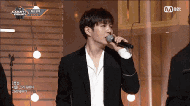 a man singing into a microphone with a mnet logo behind him