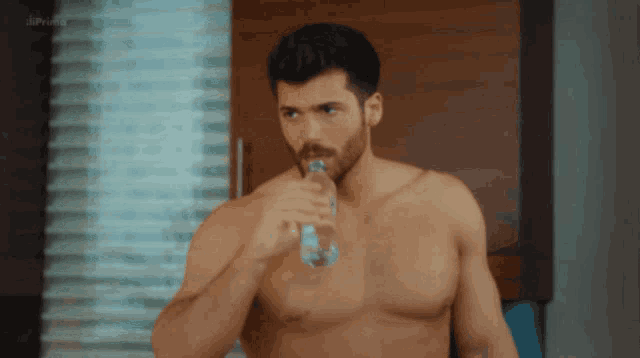 a shirtless man drinking water from a bottle with the word prime in the corner