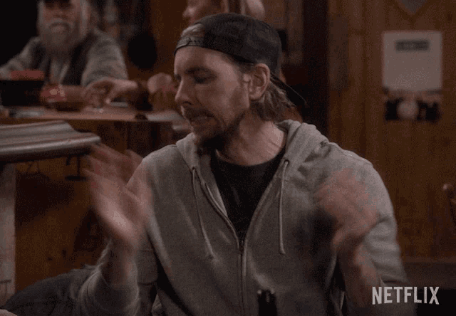 a man sitting at a table with a bottle of beer and a netflix logo in the corner