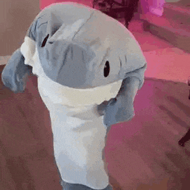 a person is wearing a stuffed shark costume and standing on a wooden floor .