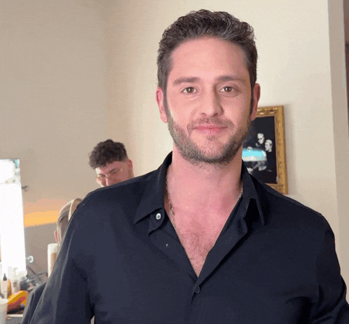 a man with a beard is wearing a black shirt and smiling