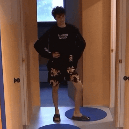 a man wearing a black shirt that says alvaro mayo stands in a hallway