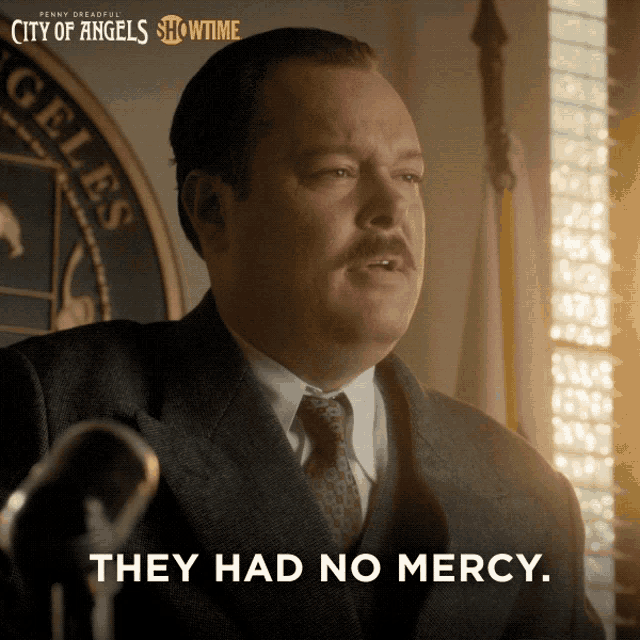 a man in a suit and tie stands in front of a microphone with the words they had no mercy below him
