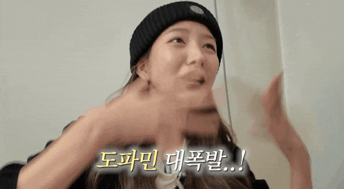 a woman wearing a black beanie is making a funny face while talking in a foreign language .