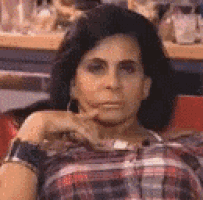 a woman is sitting on a couch with her hand on her chin and making a funny face .