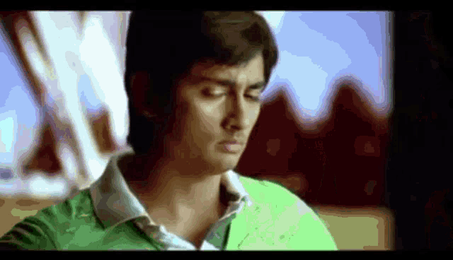 a man in a green shirt and white shirt is looking down