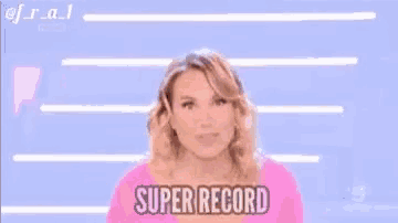 a woman in a pink shirt is standing in front of a blue background and says super record .
