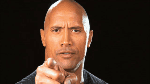 a bald man is pointing at the camera