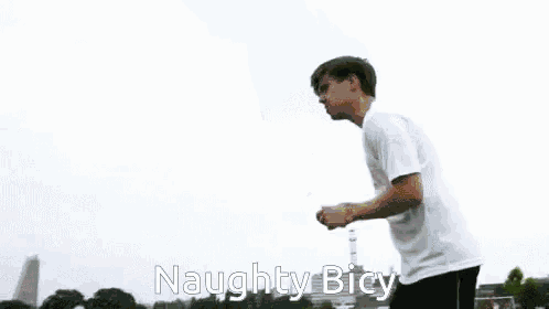 a man in a white shirt and black shorts is kicking a soccer ball with the words naughty bicy written below him
