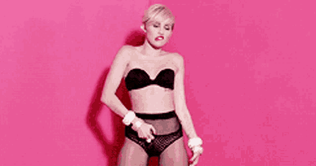 a woman in lingerie is standing in front of a pink background
