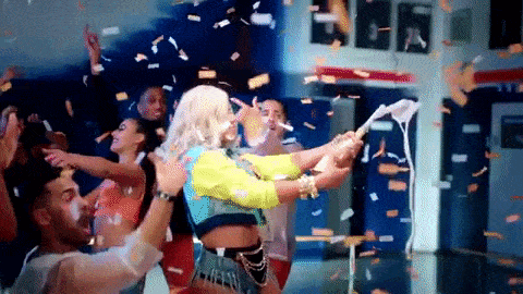 a group of people are dancing in a room with confetti falling around them .