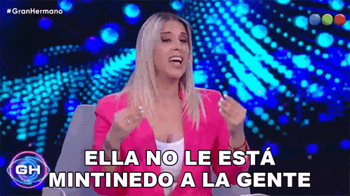 a woman in a pink jacket is sitting in front of a blue background and saying ella no le esta mintiendo a la gente