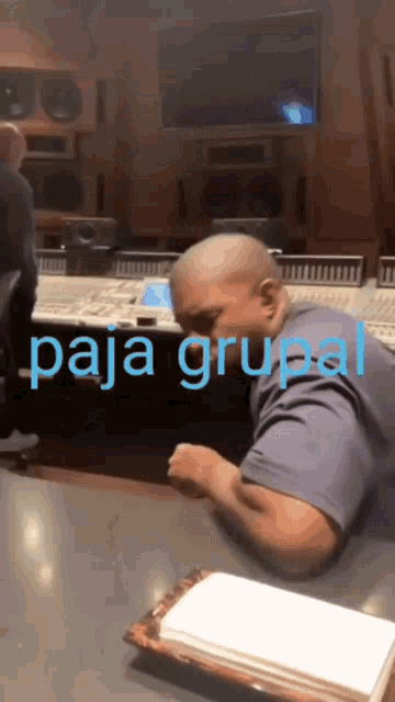 a man sitting at a table with paja grupal written on the bottom right